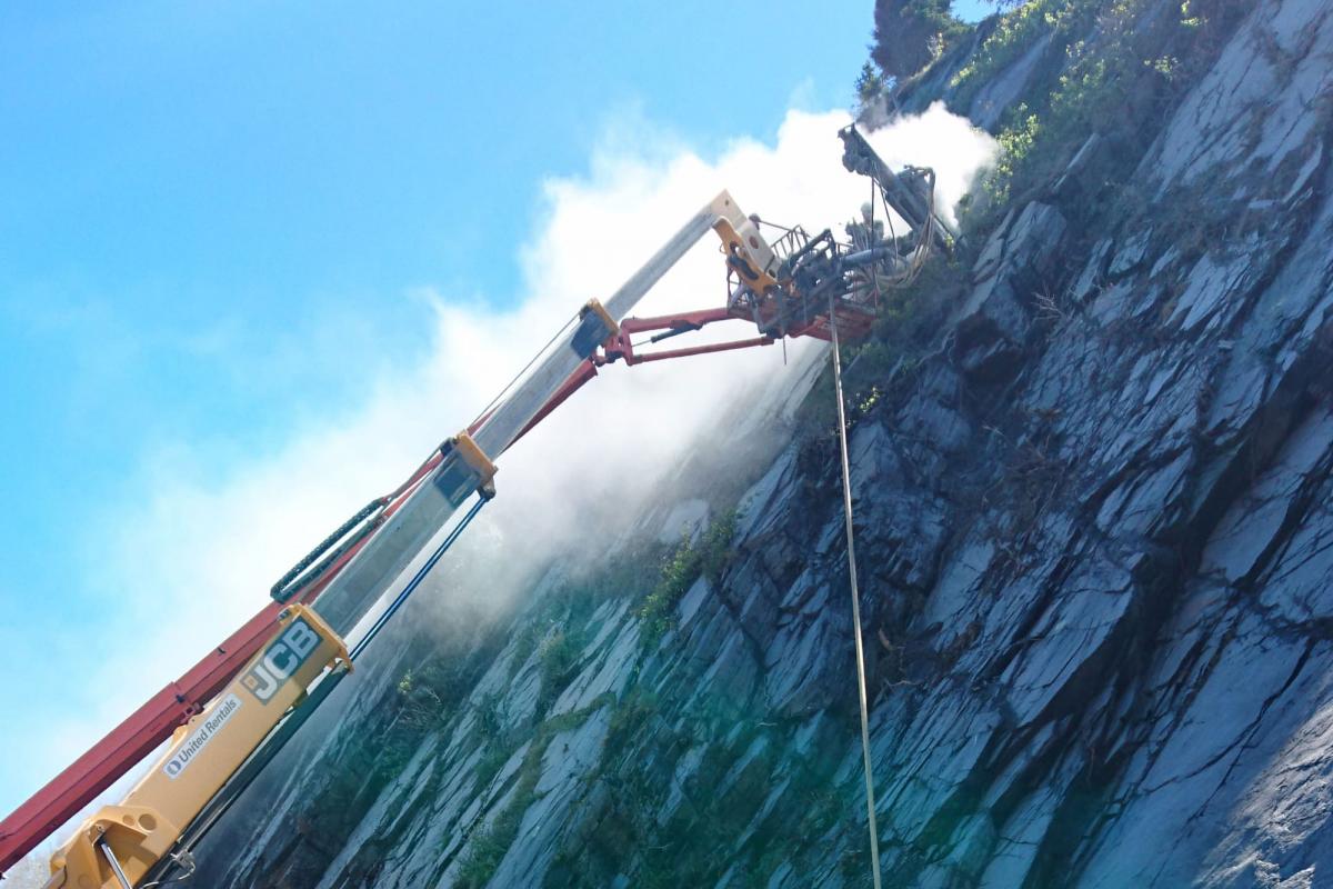 Machinery drilling into side of rock cliff