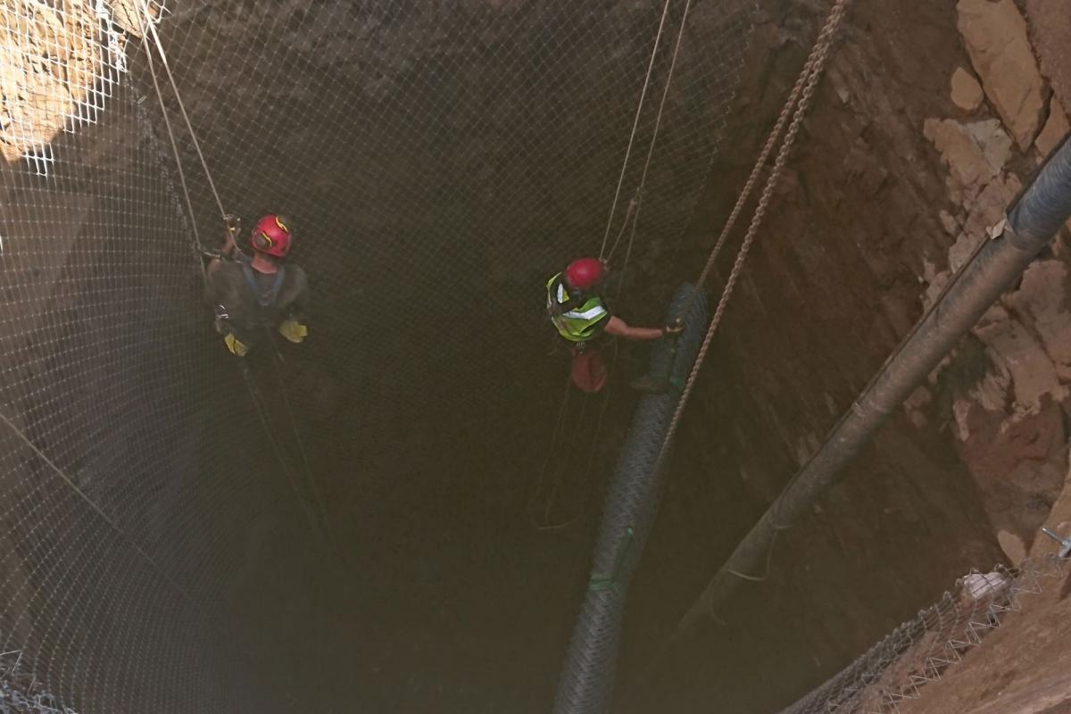 Two men securing rock in construction hole